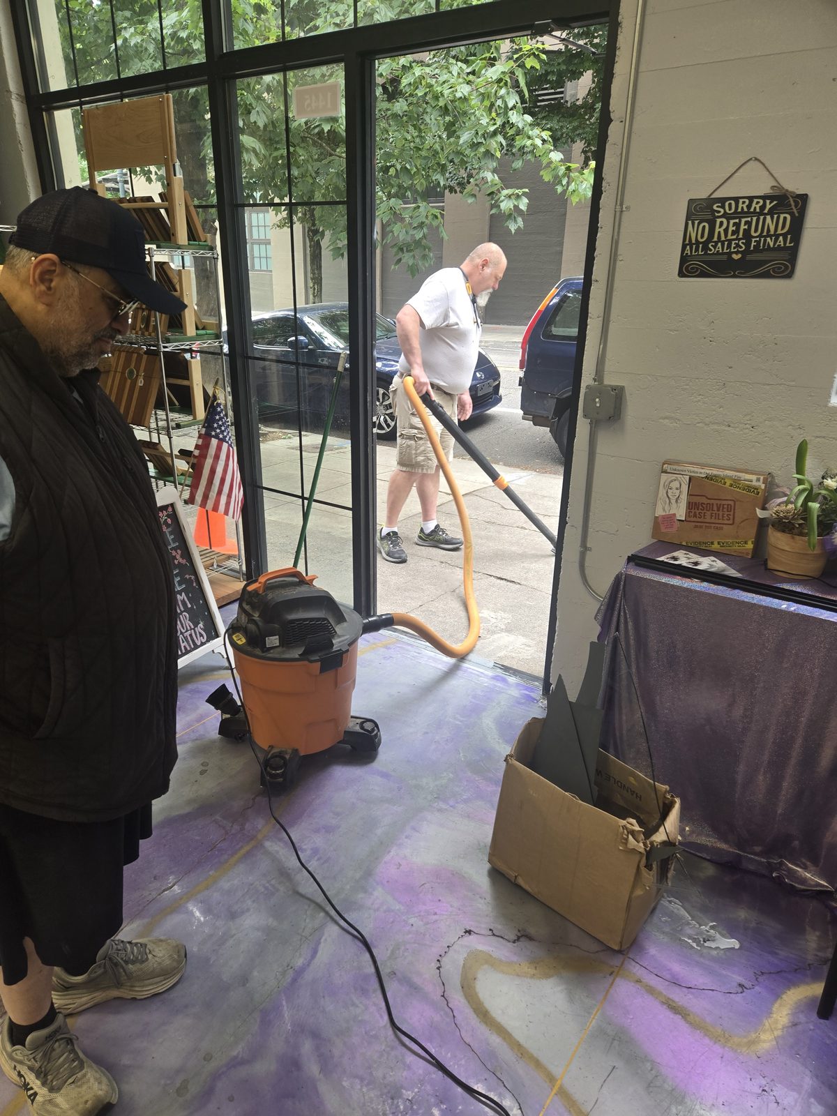 Friends and neighbors helping vacuum up broken glass inside the shop