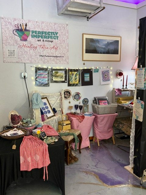 A vendor booth with art prints, vintage table displays, and handmade details